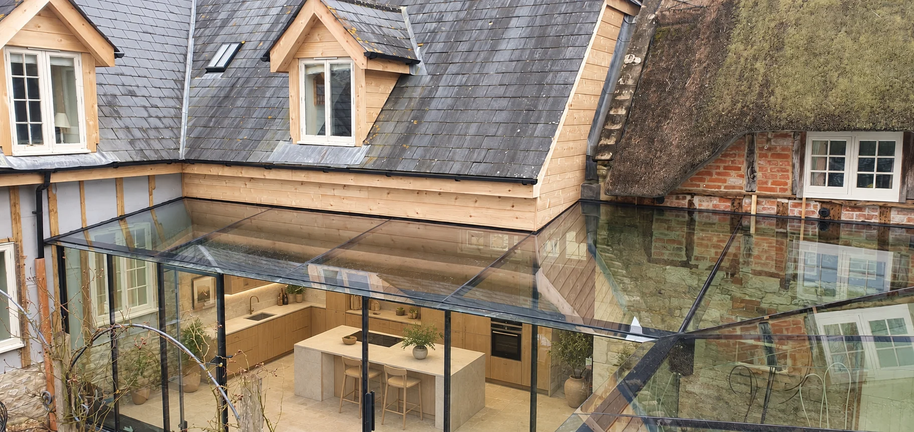 Contemporary kitchen concept beneath the Home Farm glass roof with oak cabinetry and a pale stone island