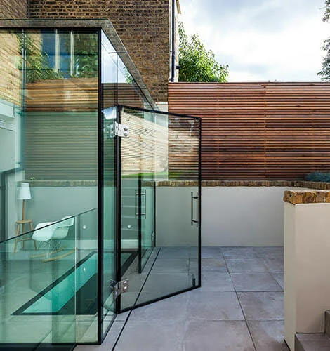 St James frameless glass extension with an open glass door beside the courtyard