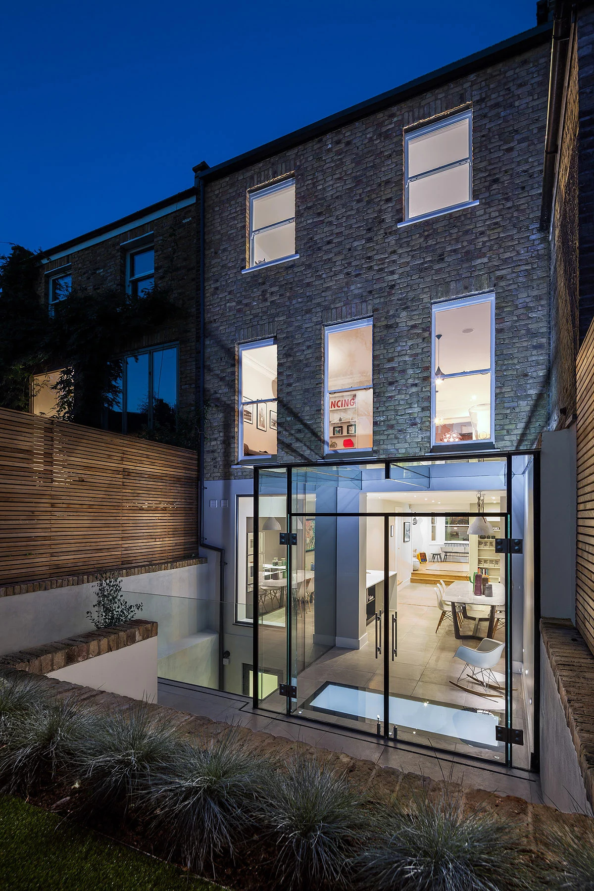 Rear of the St James house at dusk with illuminated glass extension and glass floor
