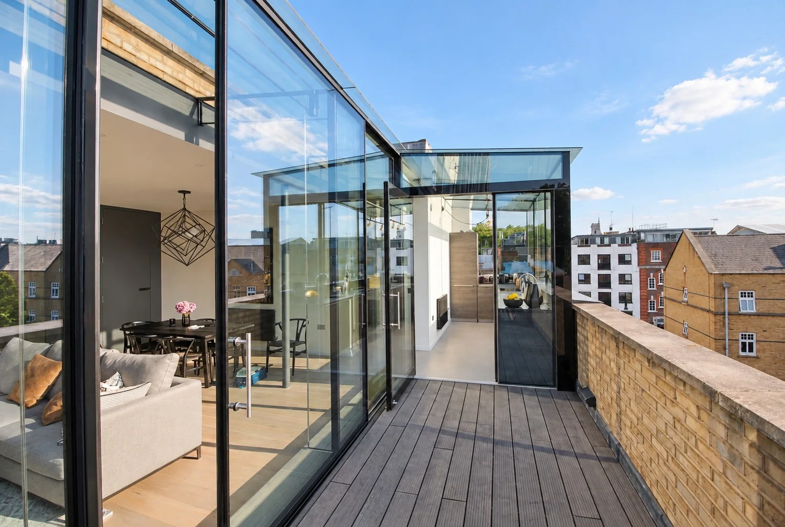 Sunlit rooftop glass extension opening onto a London terrace