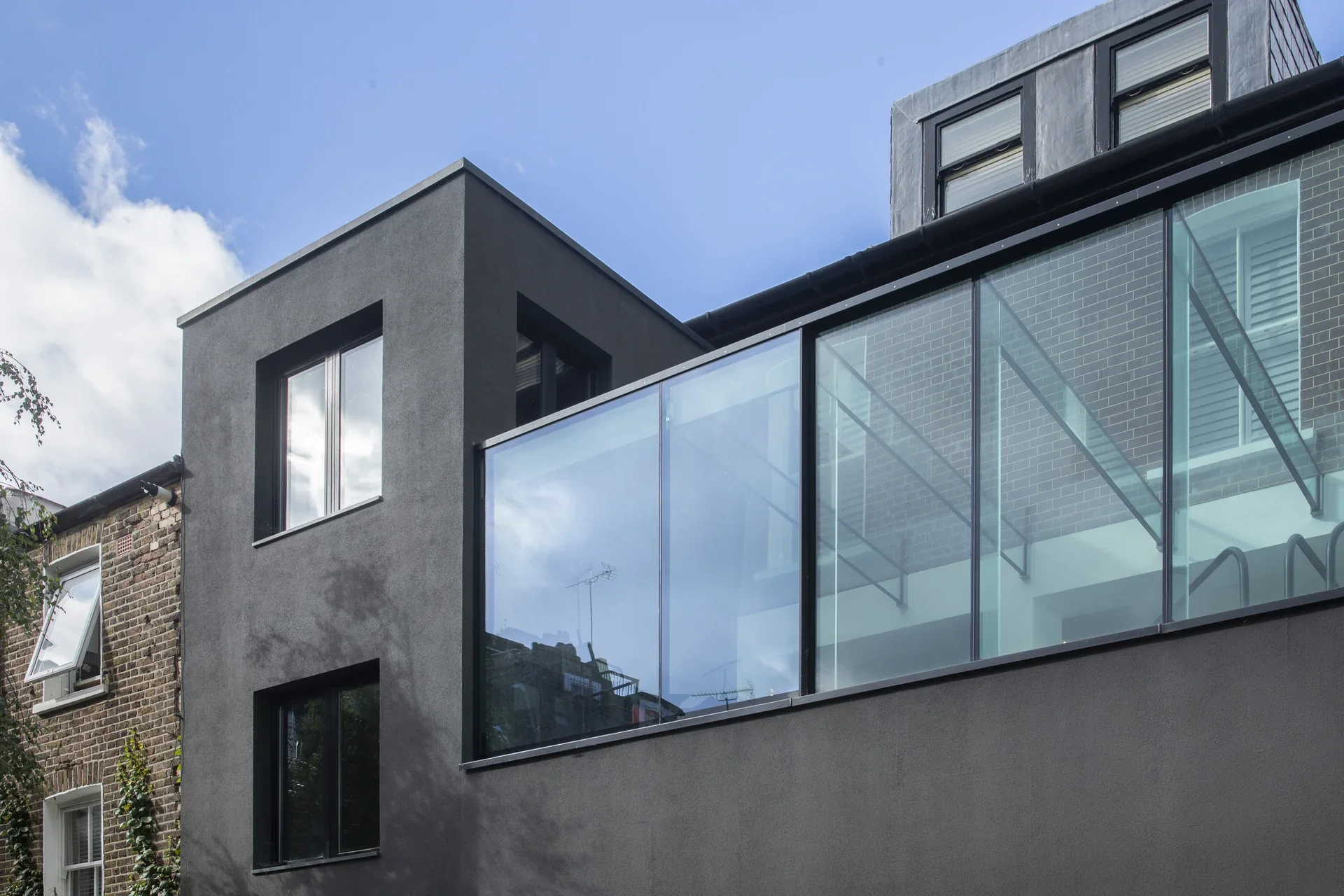 Exterior view of structural glass walls and roof beside a contemporary extension
