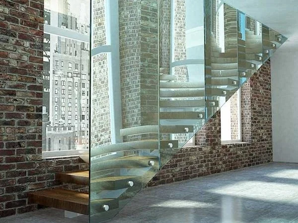 Staircase with a full-height glass stringer beside exposed brickwork and tall windows