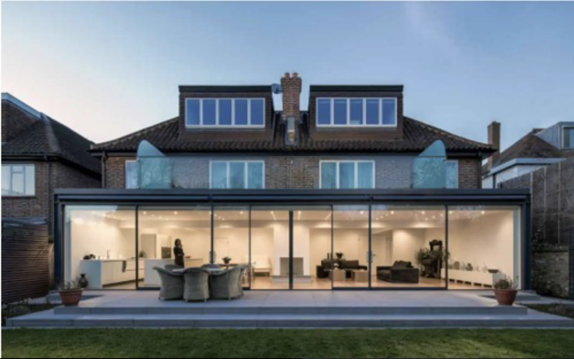 Rear house extension with wide glass doors facing a garden terrace