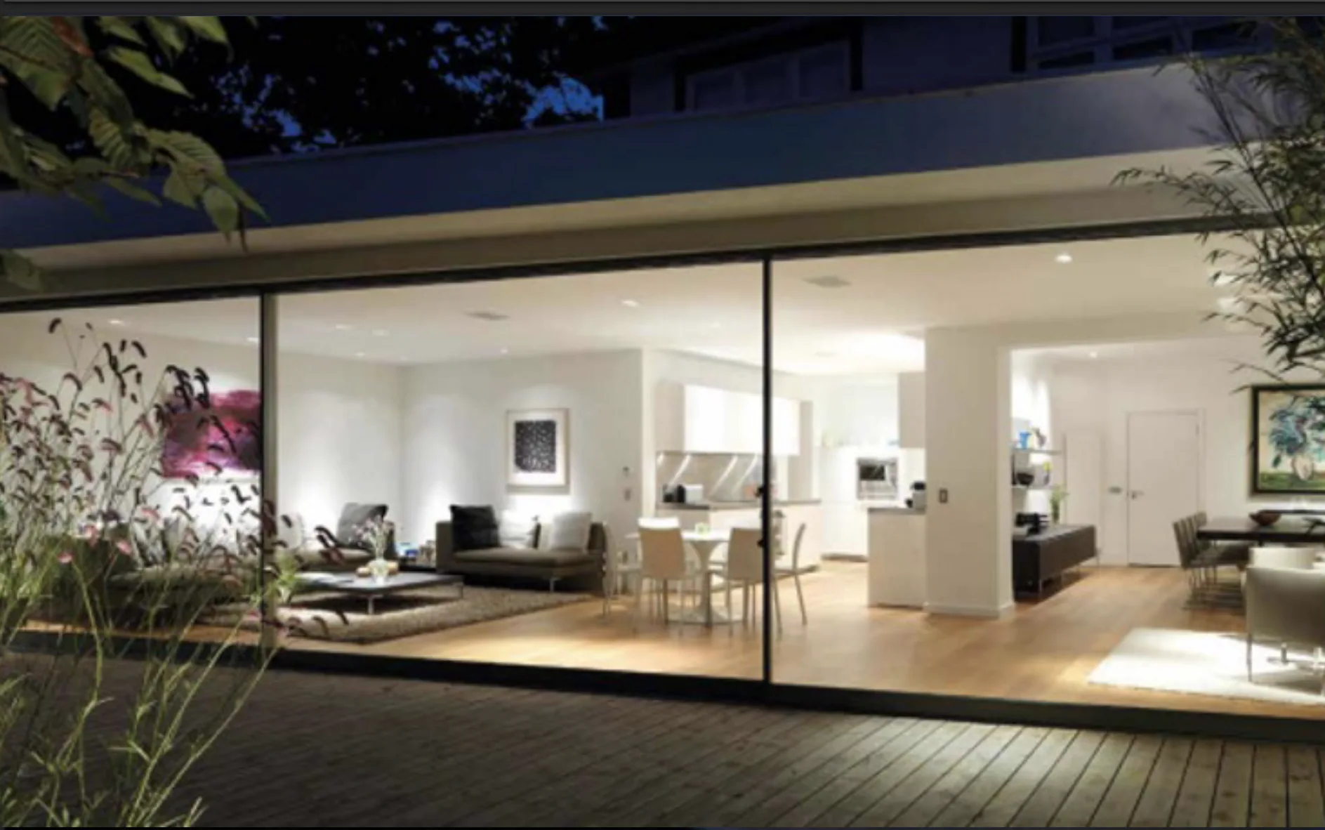 Wide glass sliding doors opening onto a garden deck at dusk